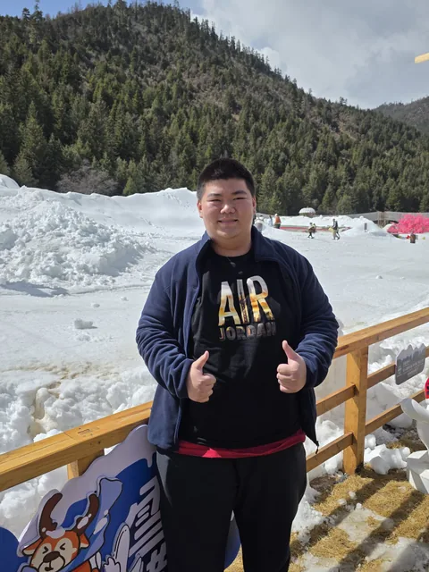 A personal travel portrait beside snow and a forested hillside.