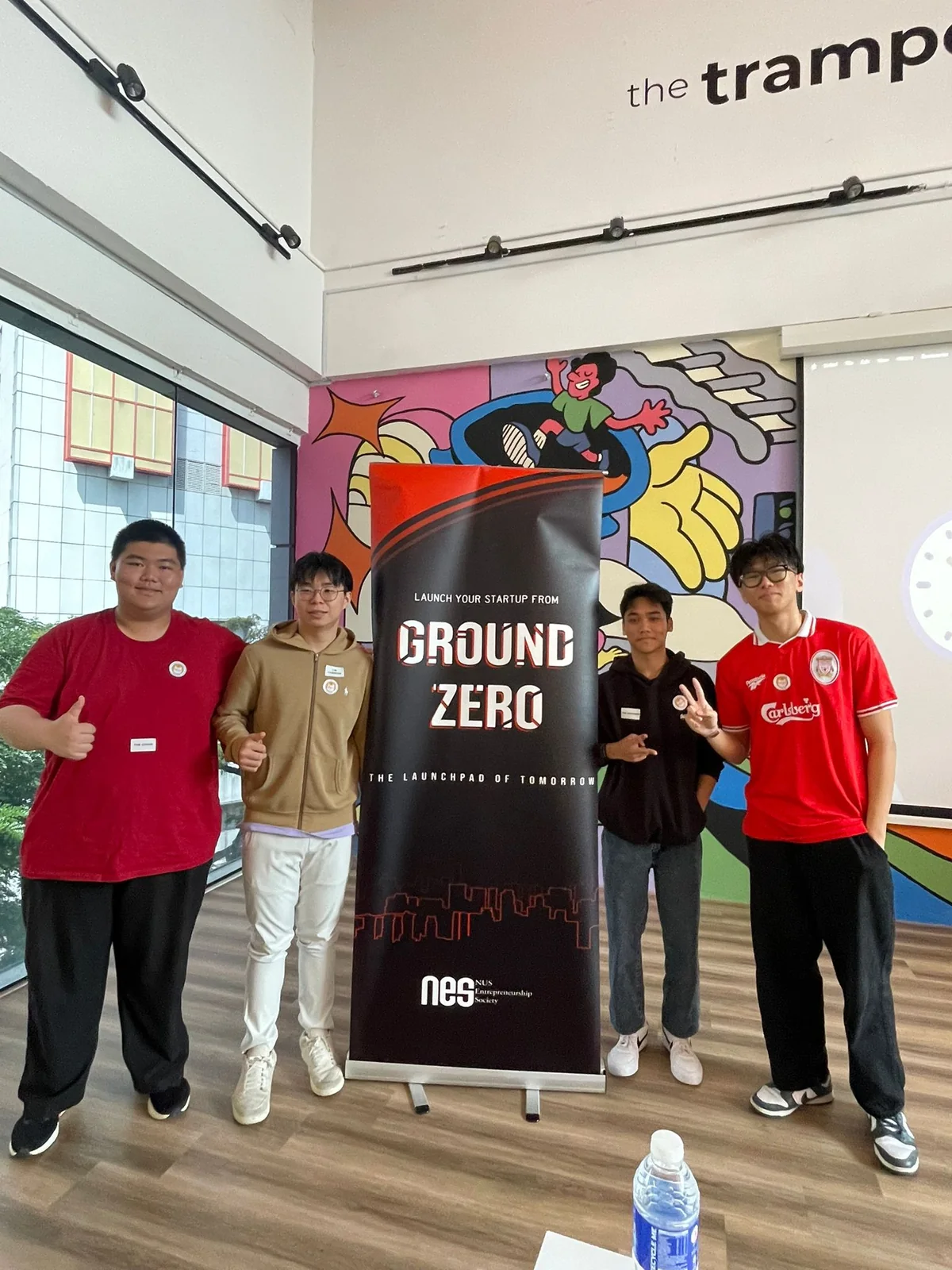 Four people posing beside a Ground Zero startup event banner.